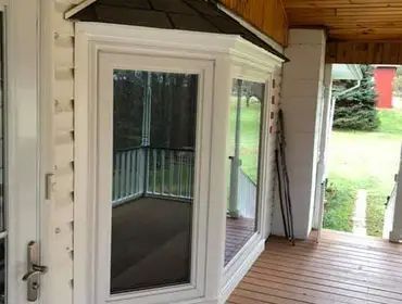 A screened in porch with a large window and a roof.