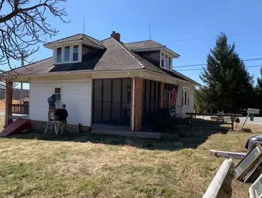 A man is standing on a ladder in front of a house.