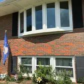 A brick house with a large bay window and a flag in front of it.