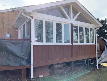 A house with a screened in porch and a deck.