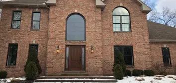 A large brick house with a large window and a wooden door.