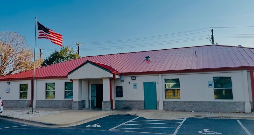 Single-story building with a red roof and U.S. flag outside on a sunny day