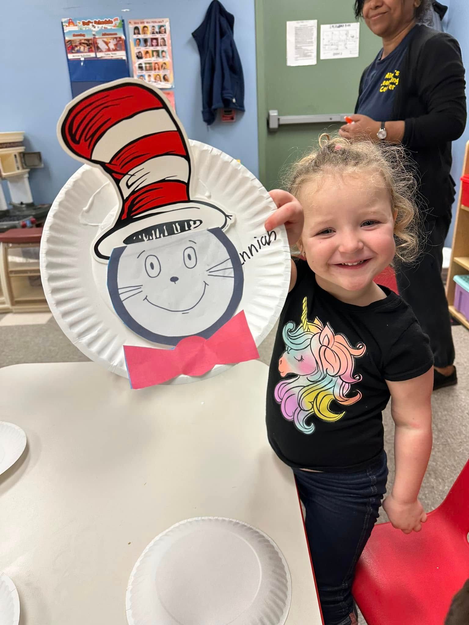 Child smiling beside a Cat in the Hat craft in a classroom setting