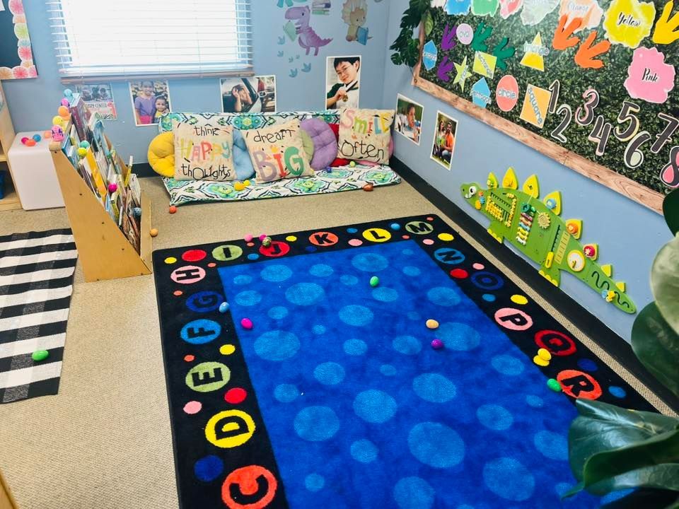 Colorful classroom reading nook with a blue rug, patterned bench, and decorated bulletin board