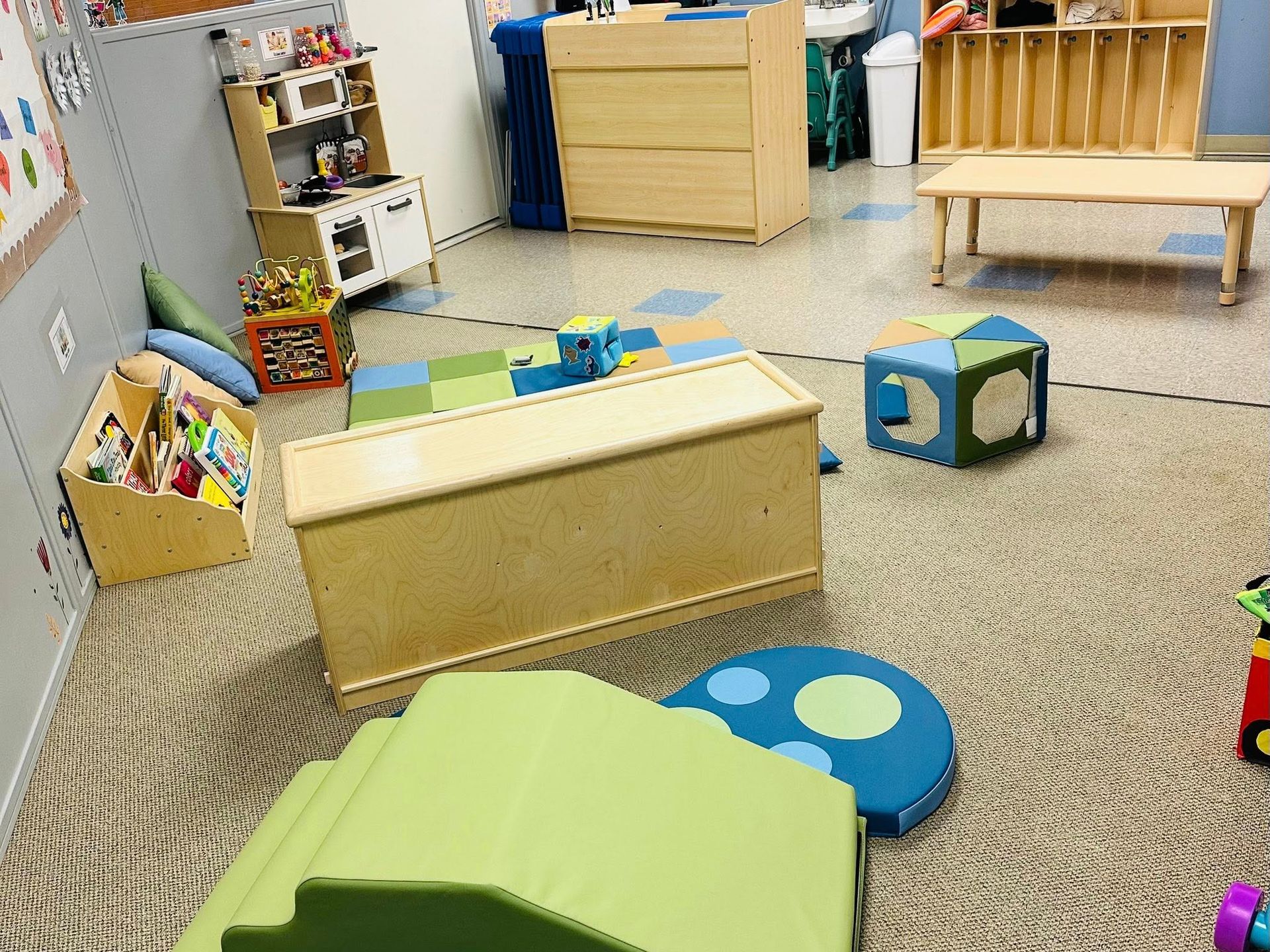 Colorful playroom with foam blocks, low benches, and toy shelves on a carpeted floor.