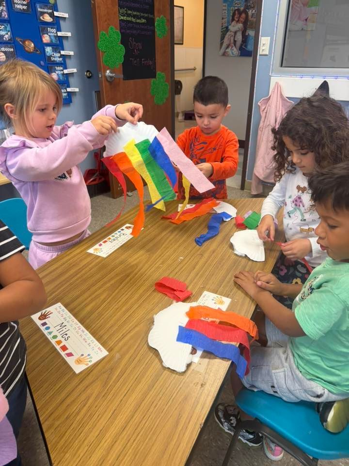 Children at a table making colorful paper crafts in a classroom