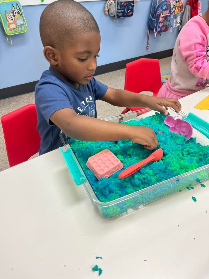 Child playing with colorful sensory bin at a classroom table