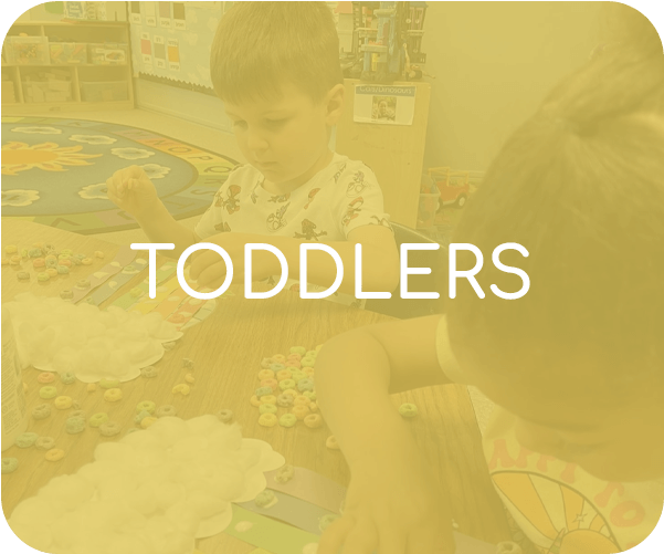 Toddlers playing at a classroom table with toys under a yellow tint