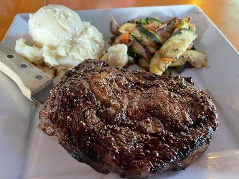 A white plate topped with a steak , mashed potatoes and vegetables.