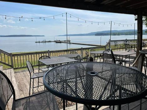 A table and chairs on a deck overlooking a lake.