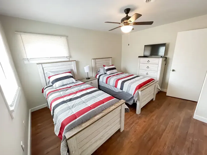 A bedroom with two twin beds and a ceiling fan.