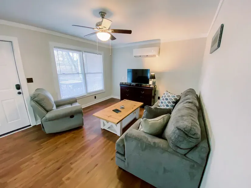 A living room with a couch , chair , coffee table and television.