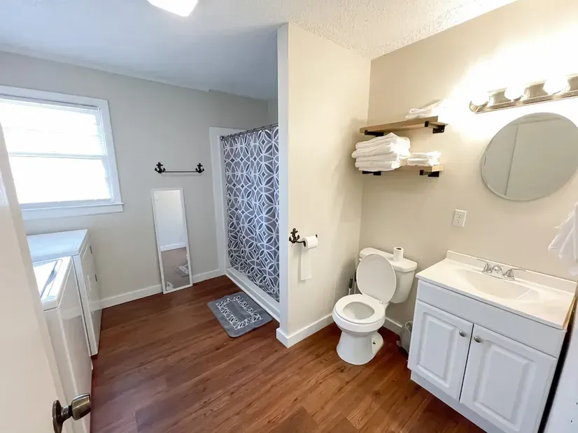 A bathroom with a toilet , sink , mirror and shower.