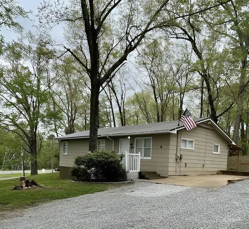 A small house with a flag on the side of it is surrounded by trees.
