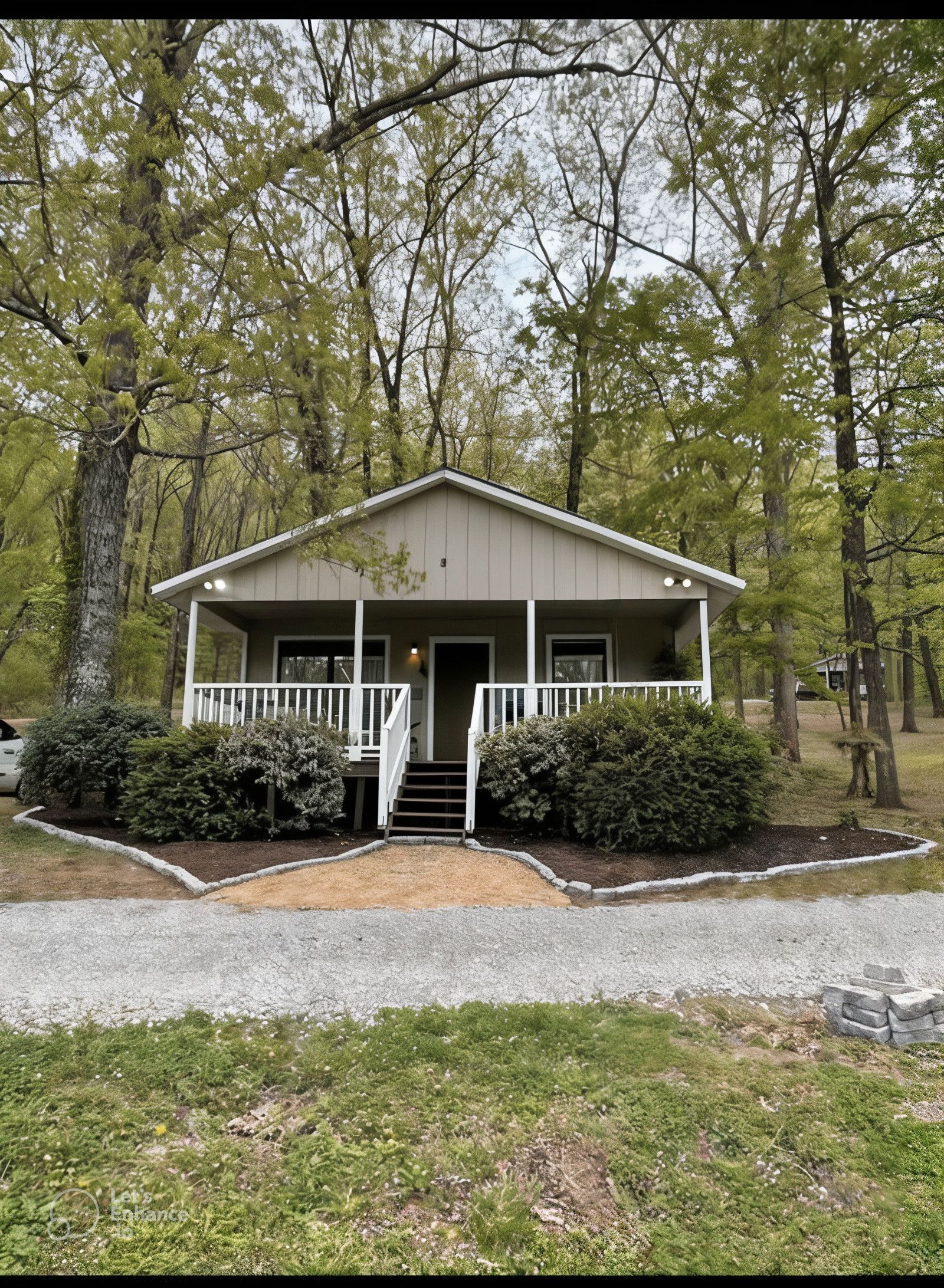 A small house with a porch in the middle of a forest.