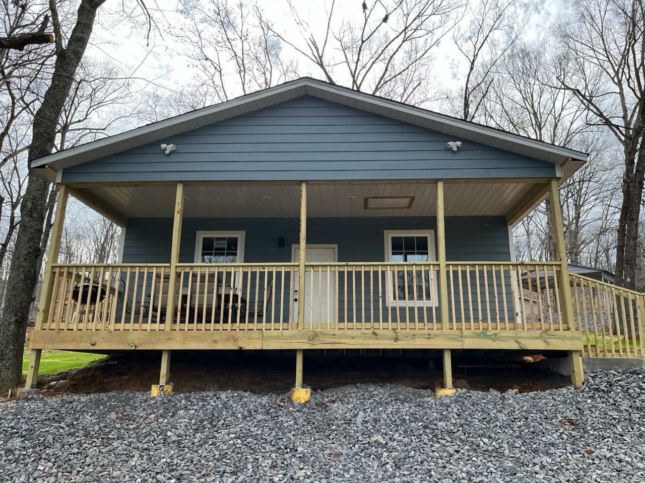 A blue house with a large porch and a wooden deck.