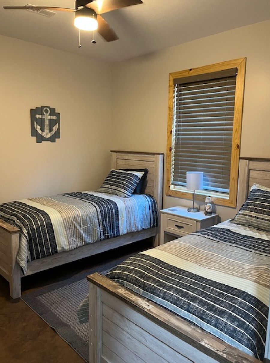 A bedroom with two twin beds and a ceiling fan.