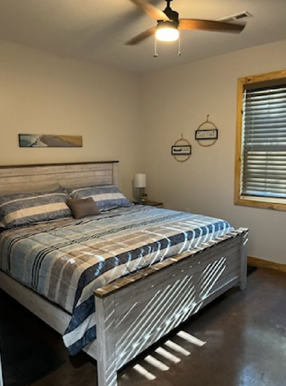 A bedroom with a bed and a ceiling fan