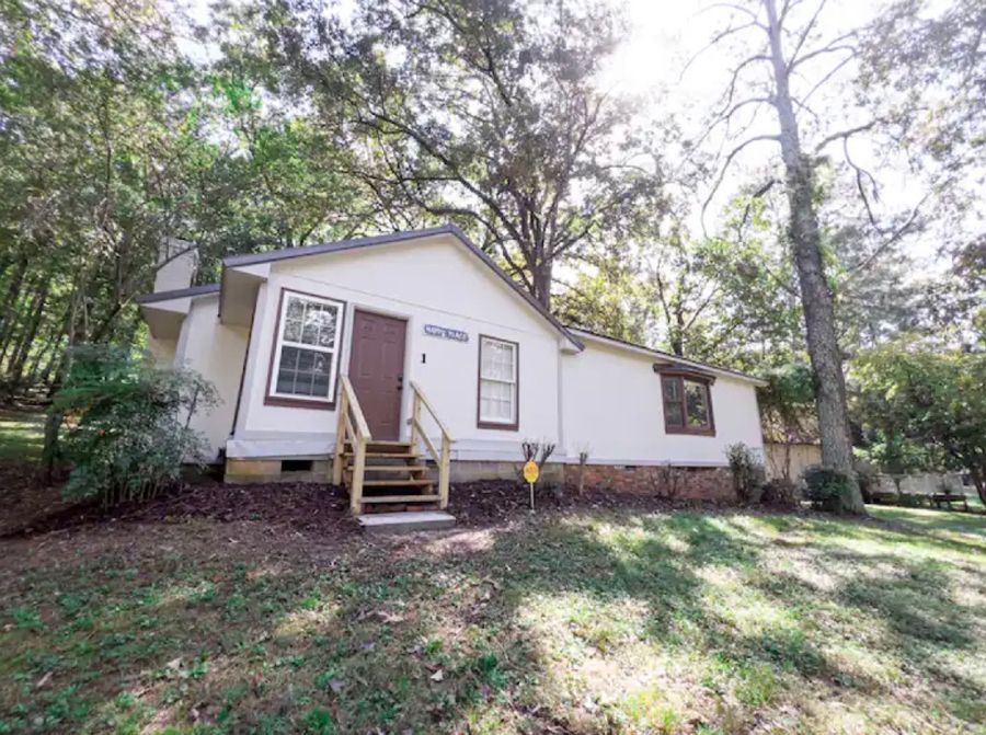 A white mobile home is sitting on top of a lush green hillside surrounded by trees.