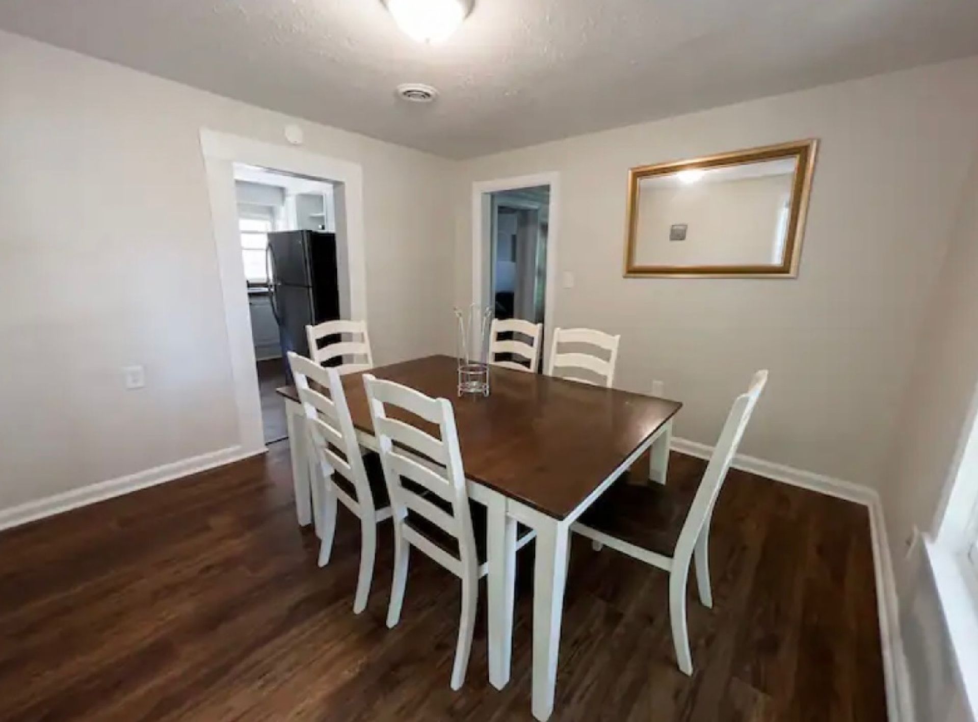 A dining room with a table and chairs and a mirror on the wall.