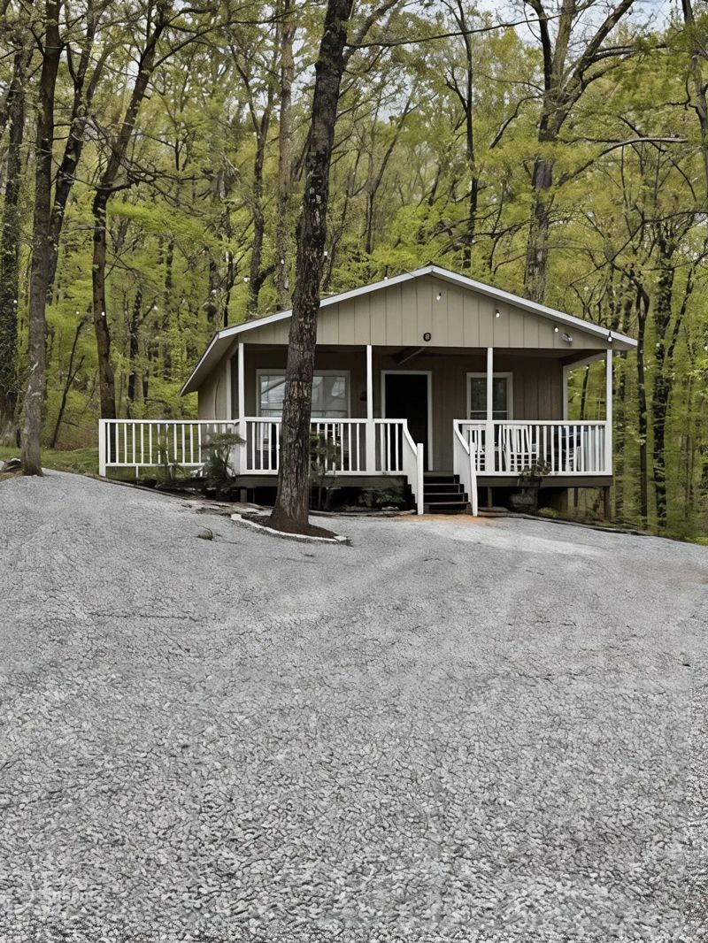 A small house with a porch in the middle of a forest.