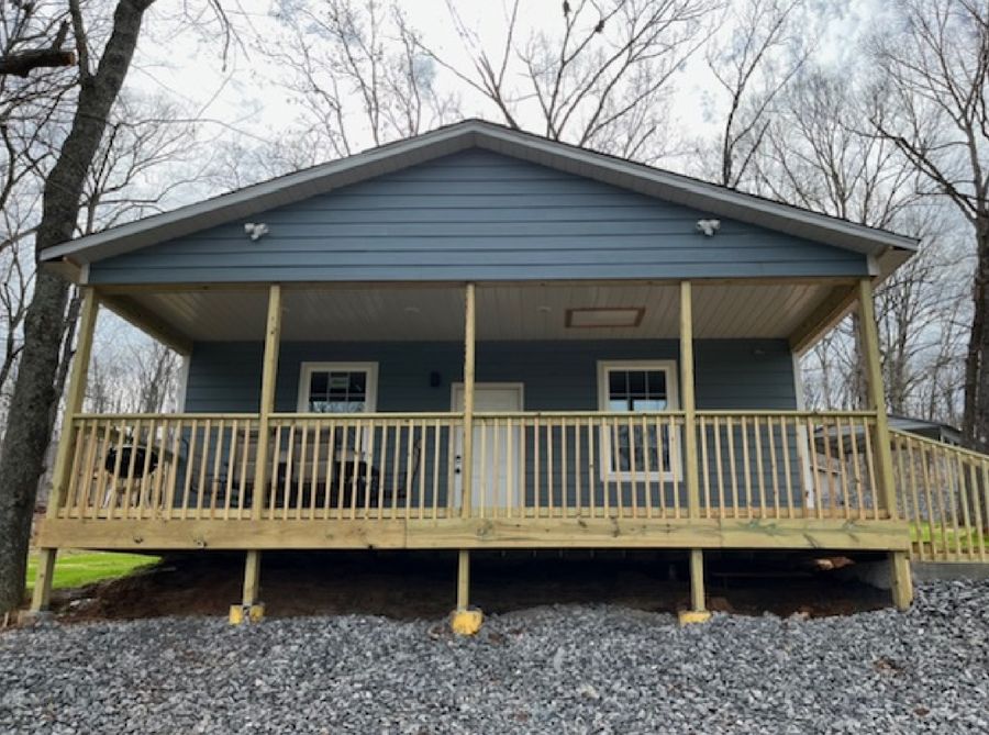 A blue house with a large porch and a wooden deck.