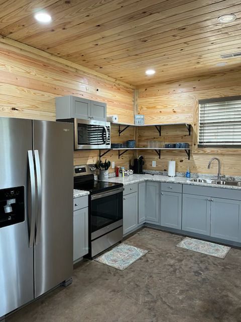 A kitchen with stainless steel appliances and wooden walls