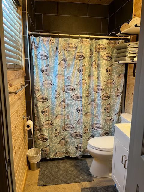 A bathroom with a shower curtain with fish on it