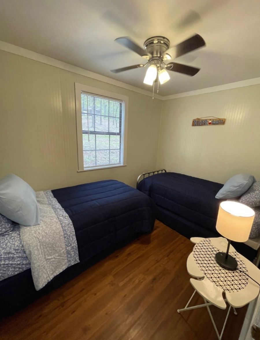 A bedroom with two beds and a ceiling fan