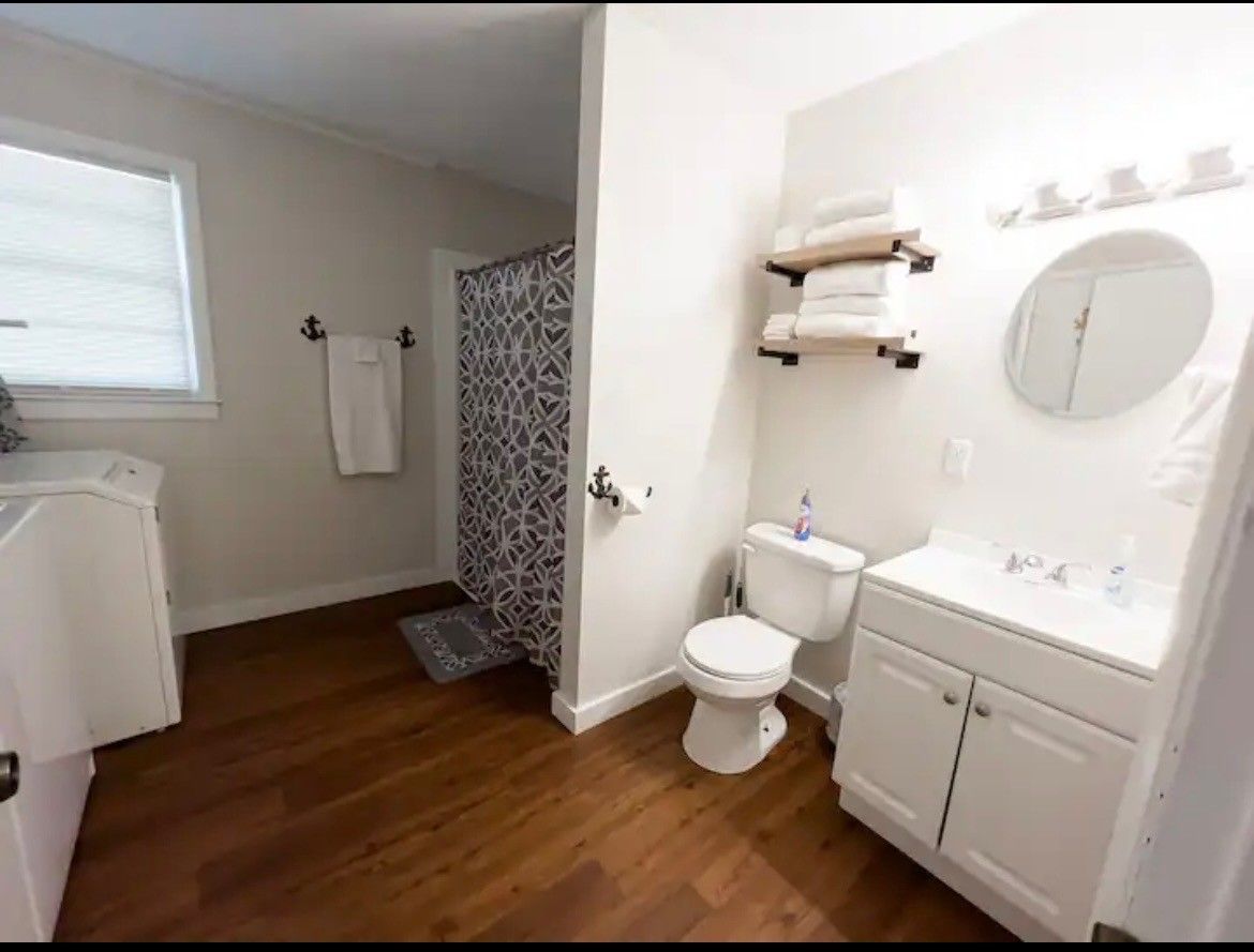 A bathroom with a toilet , sink , mirror and shower curtain.