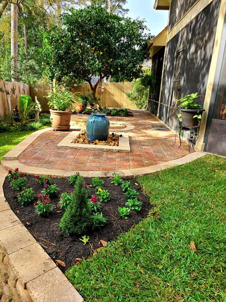 A patio with a fountain in the middle of it and a tree in the background