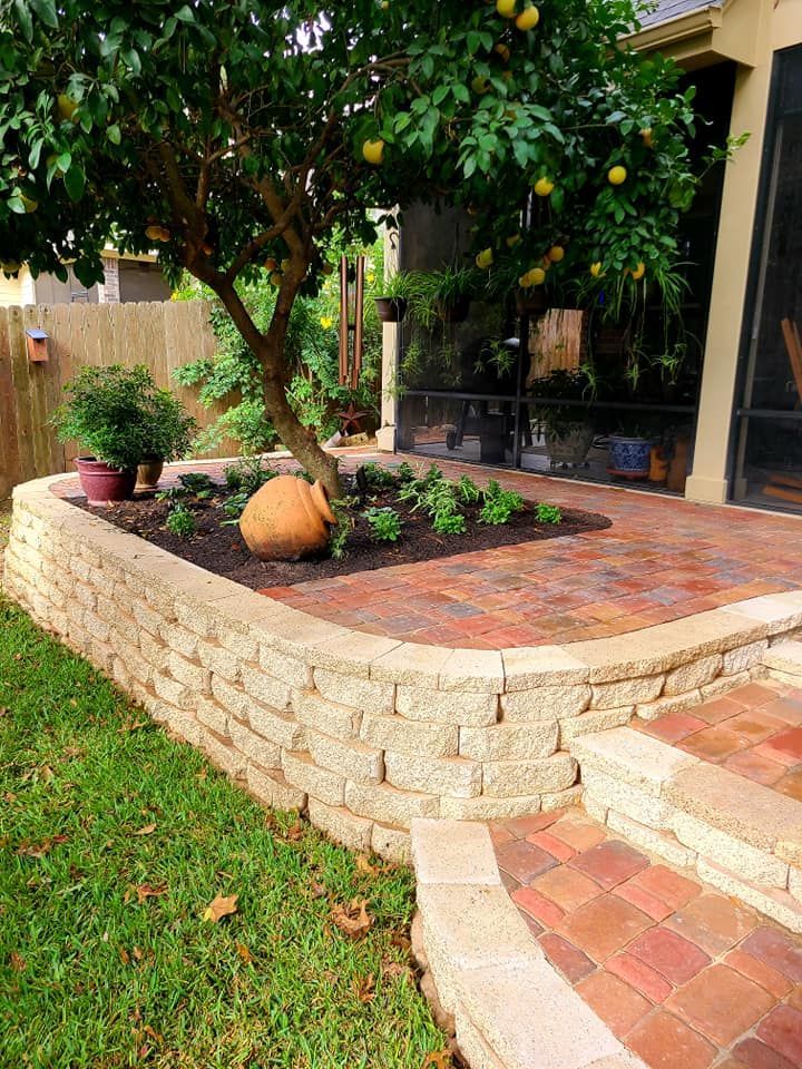A brick wall surrounds a patio with a tree in the middle of it