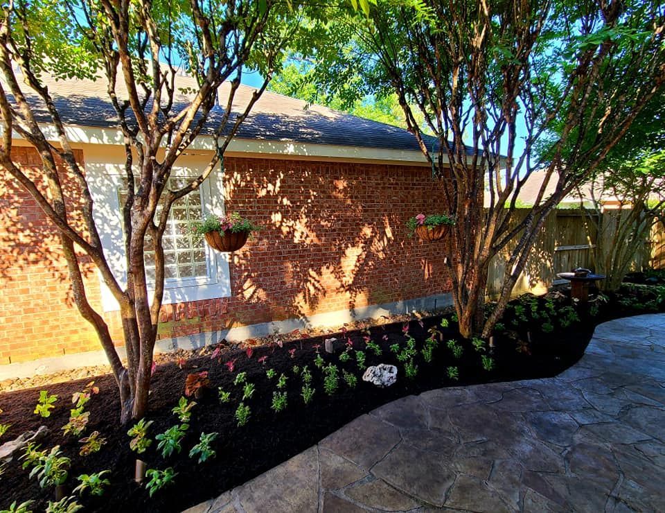 A brick house with a lush green garden in front of it