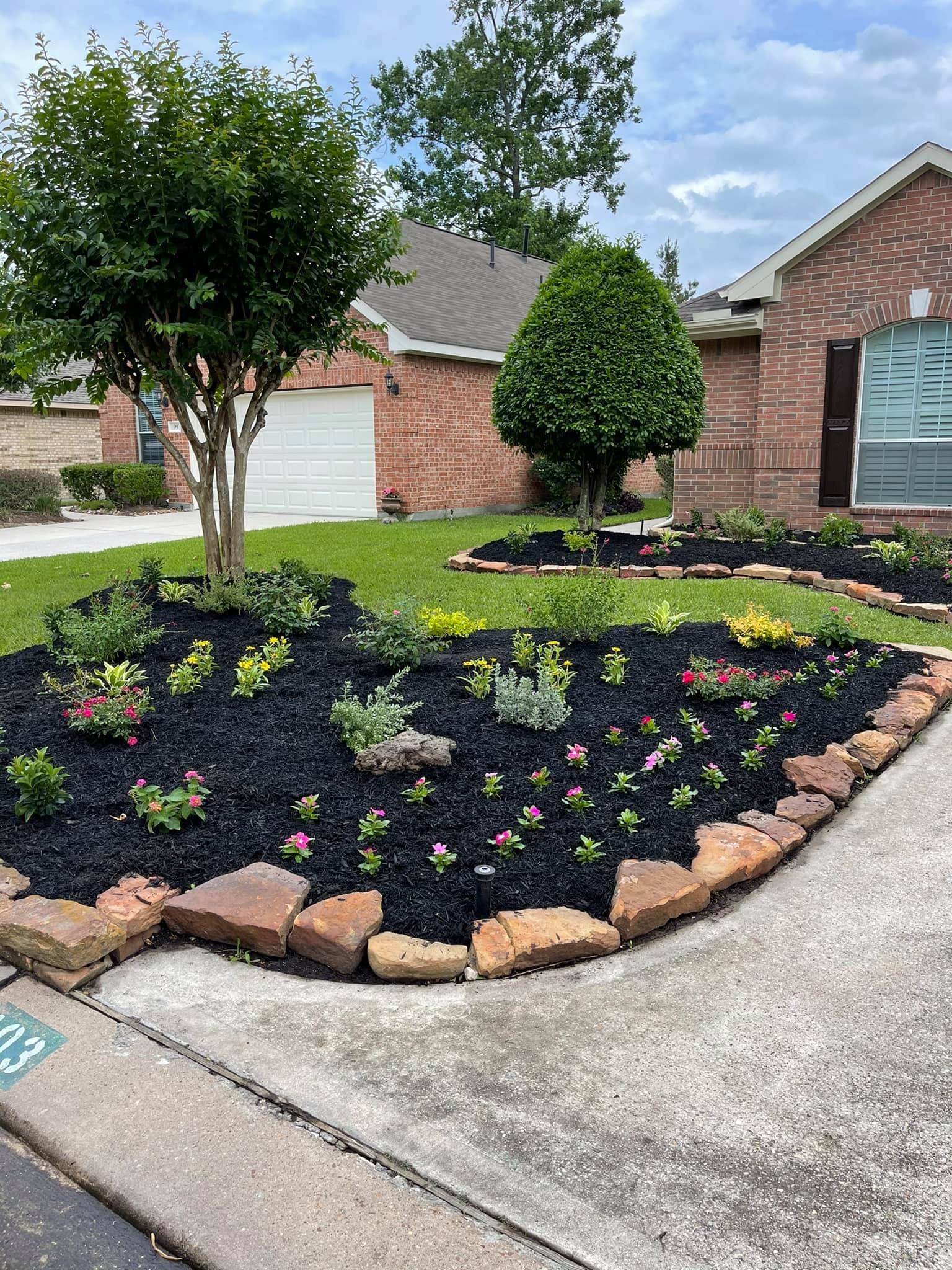 A lush green yard with a circular garden in front of a brick house