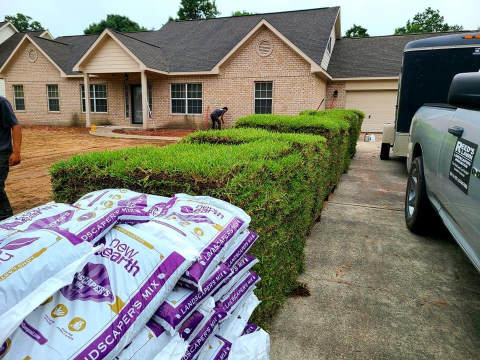 A truck is parked in front of a house with bags of dirt in front of it