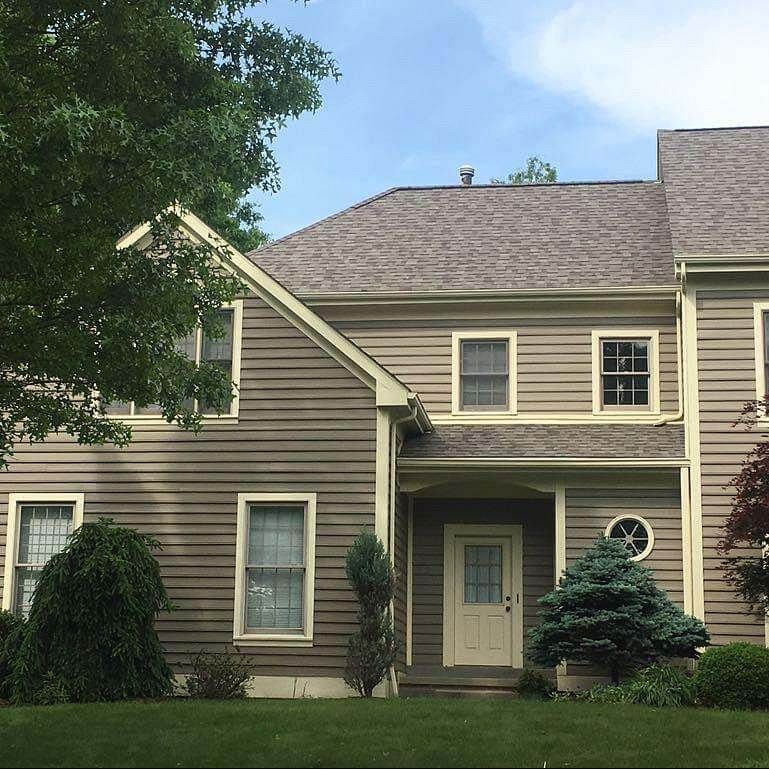 A large brick and white house with a lush green lawn in front of it.