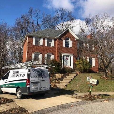 A white van is parked in front of a large brick house.
