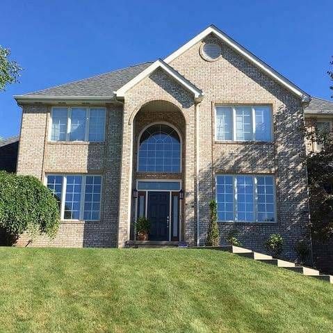A large brick house with a lush green lawn in front of it.