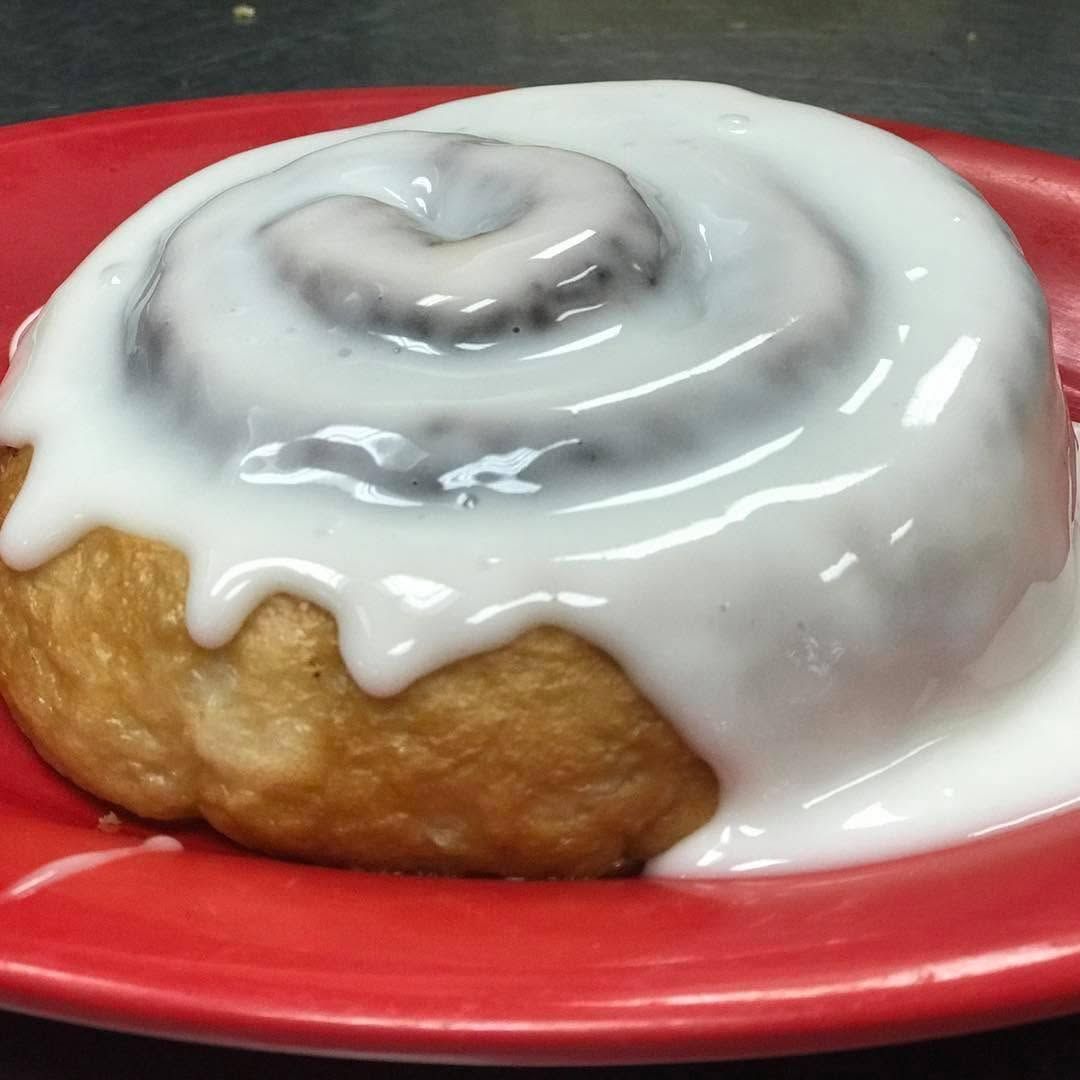 Cinnamon roll with white icing on a red plate