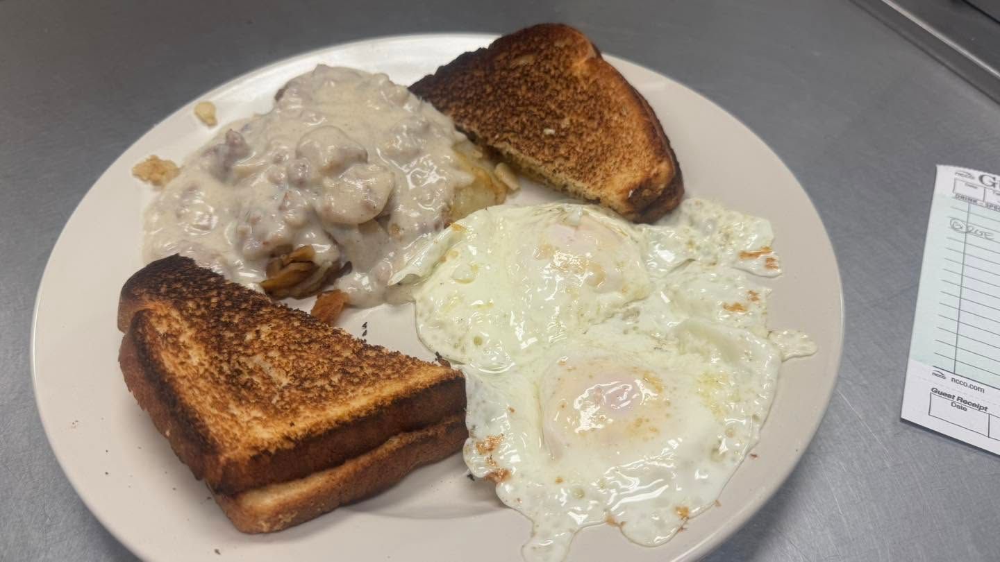 Plate with toast, two fried eggs, and creamy gravy on a table