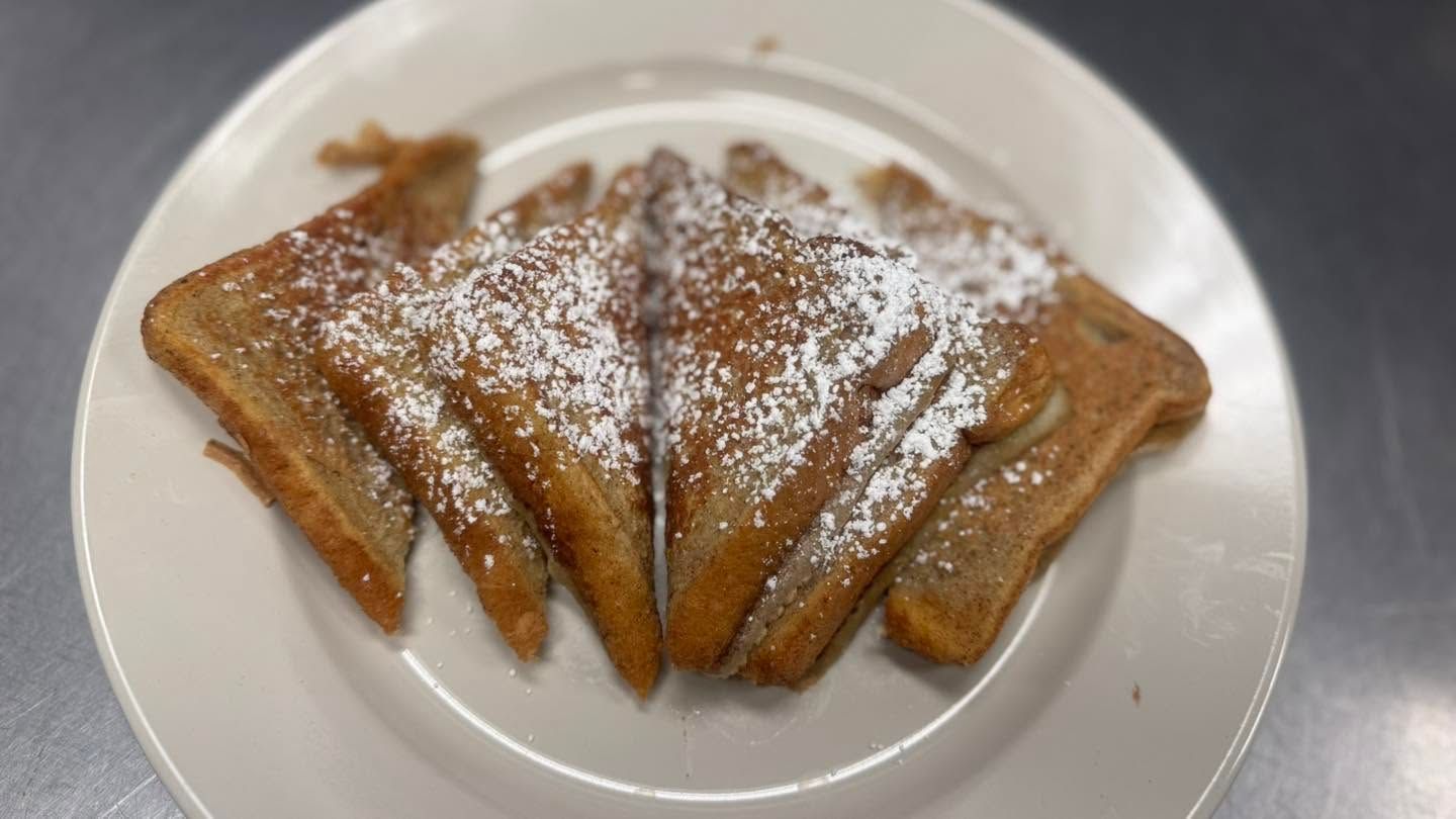 Powdered sugar-dusted French toast triangles on a white plate