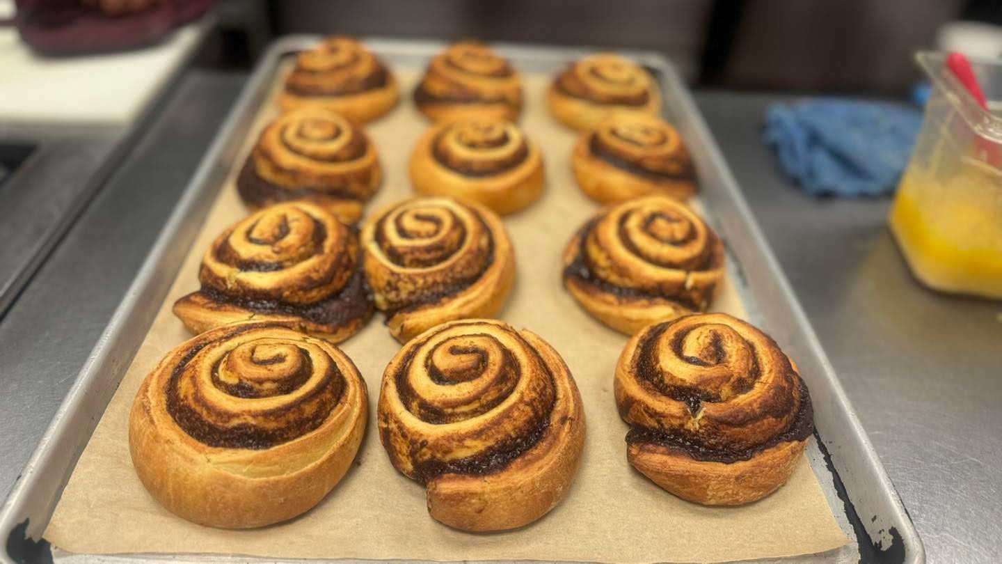 A bunch of cinnamon rolls are sitting on a tray on a table.