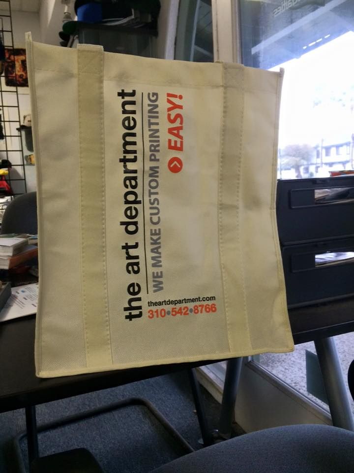 Off-white tote bag with the art department logo and contact information on it.
