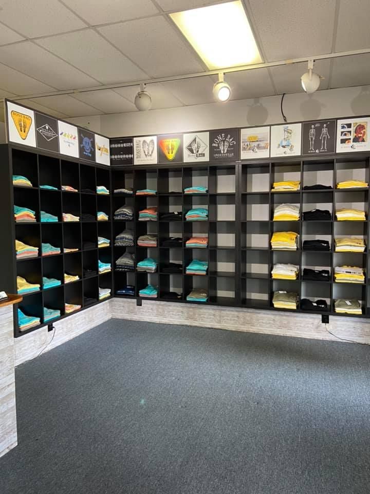 Shelves displaying folded shirts, with graphic art above, in a clothing store.