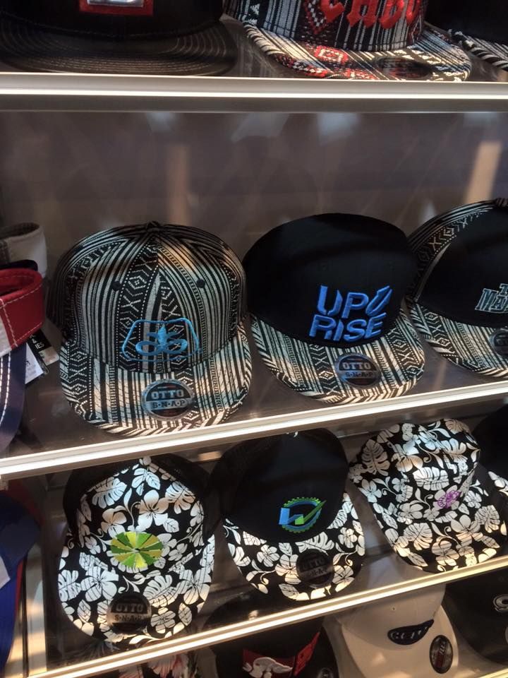 Hats on display in a store. Several snapback caps with various patterns and logos are visible on shelves.