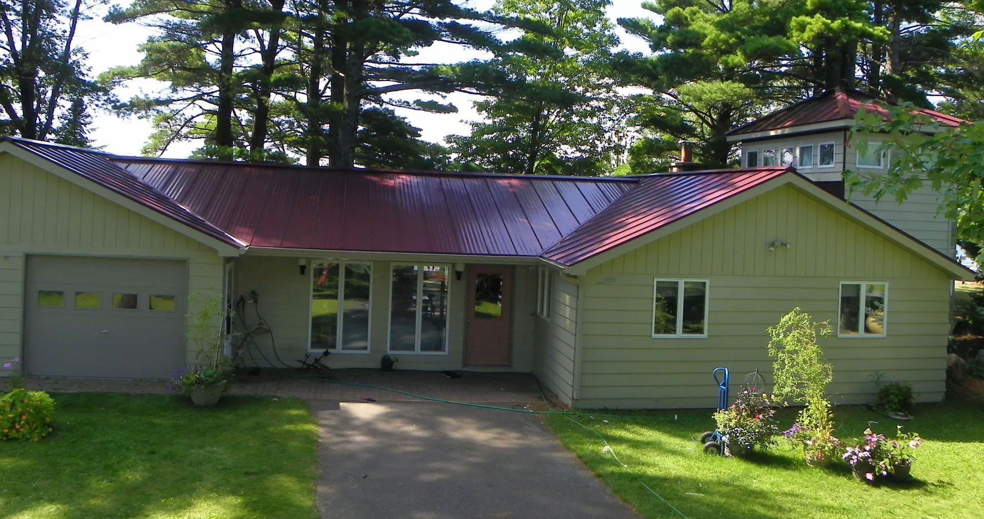 Single-story house with red roof, attached garage, and driveway in a green yard