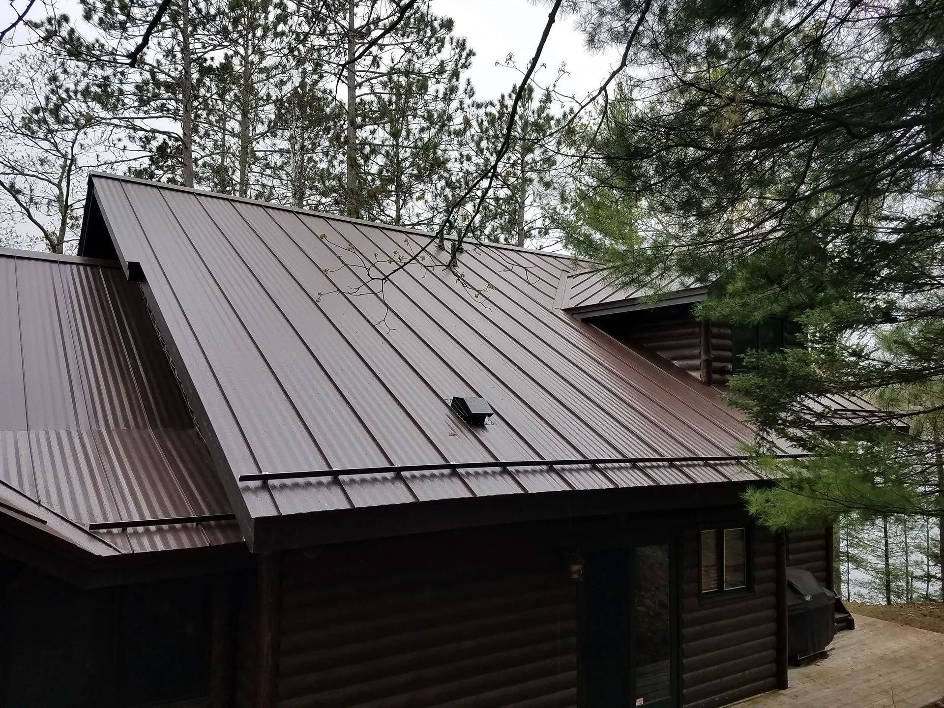 Brown metal roof on a cabin surrounded by trees