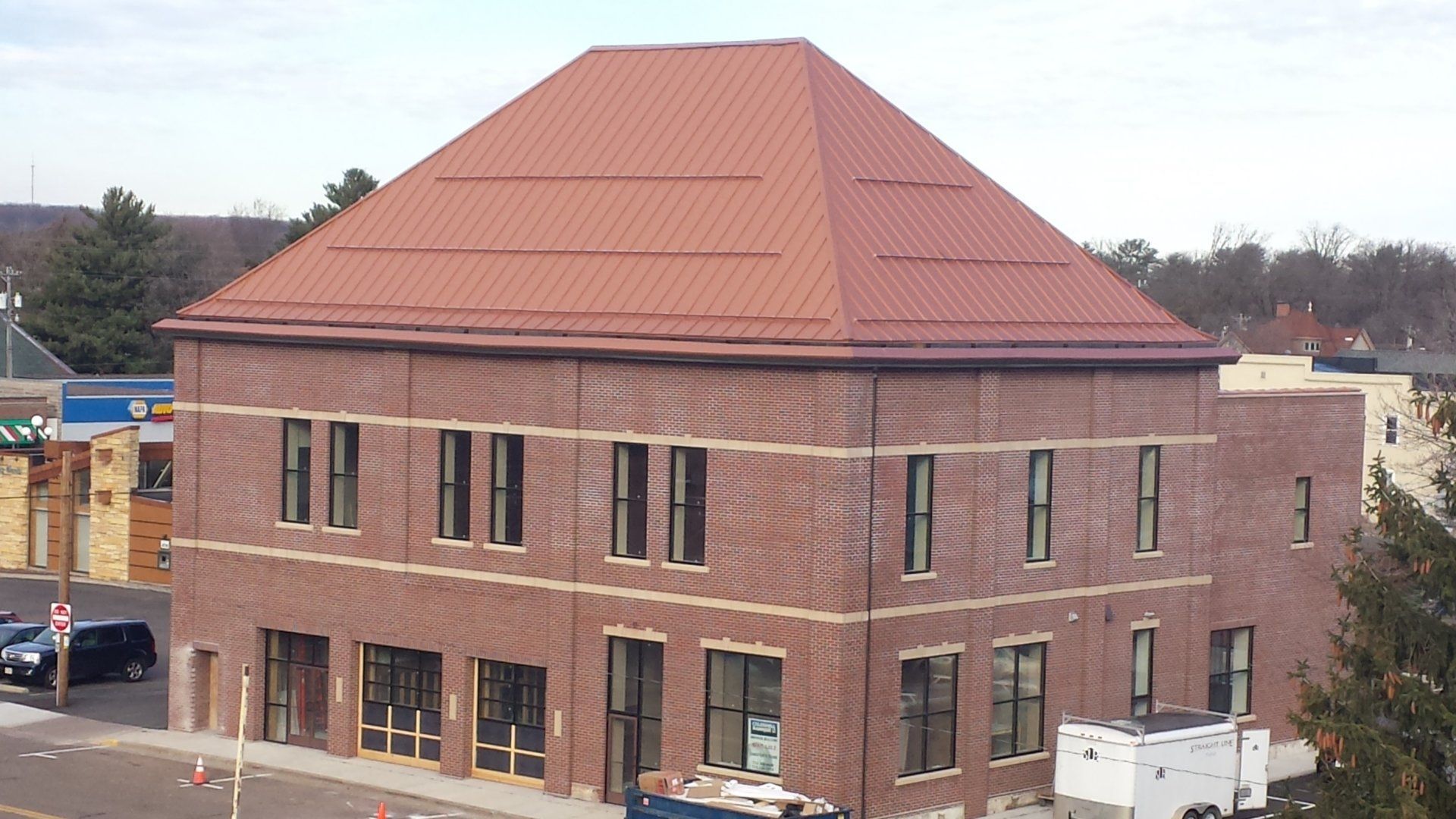 Brick building with a red roof under construction on a street corner
