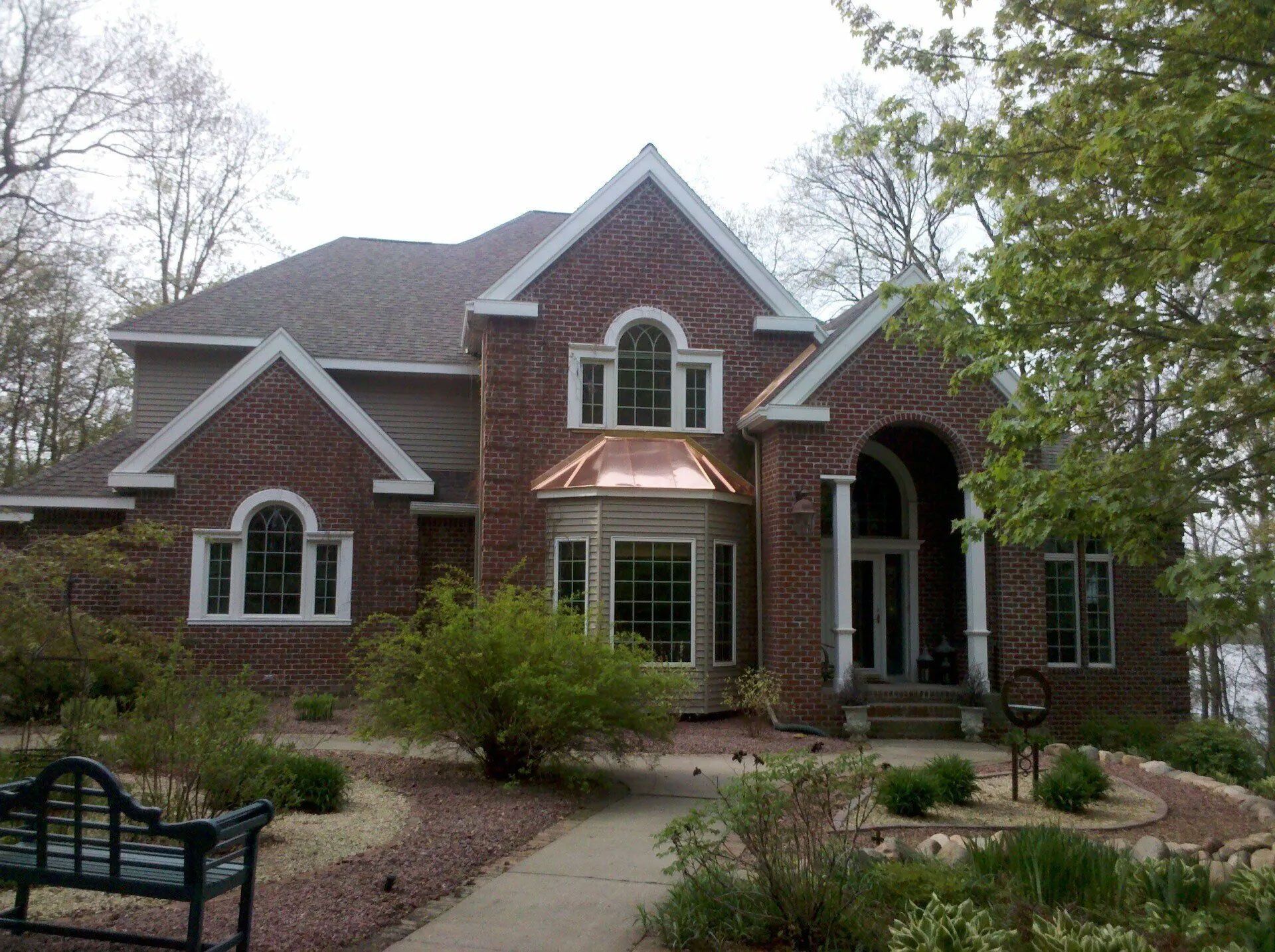 Brick suburban house with arched entry, gabled roof, and landscaped front yard
