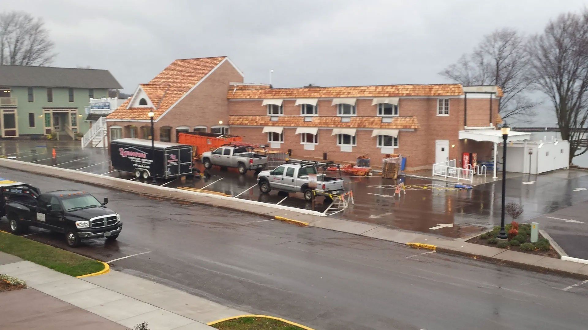 Wet street outside a brick building with parked cars and a fallen awning in rainy weather